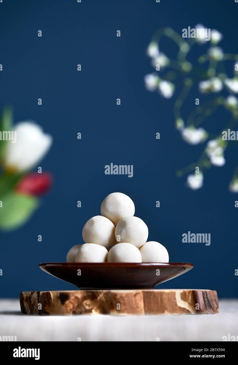 Kazakh and Kyrgyz national food kurt white salty balls from dry cheese around flowers during Nauryz festival at dark blue background. Free space for y Stock Photo