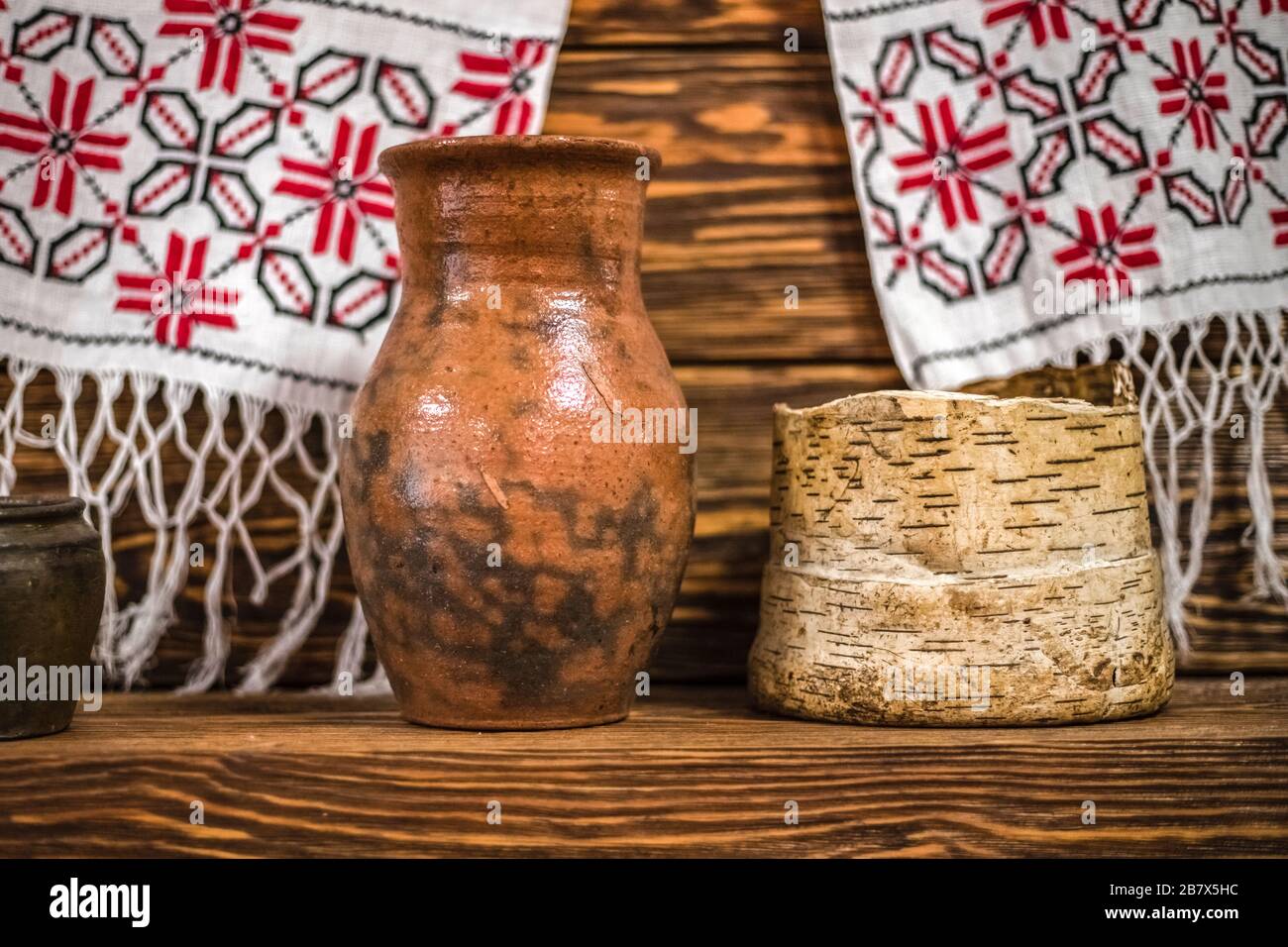 Old Russian clay krynka for milk on a wooden shelf. handmade ceramic dishes Stock Photo