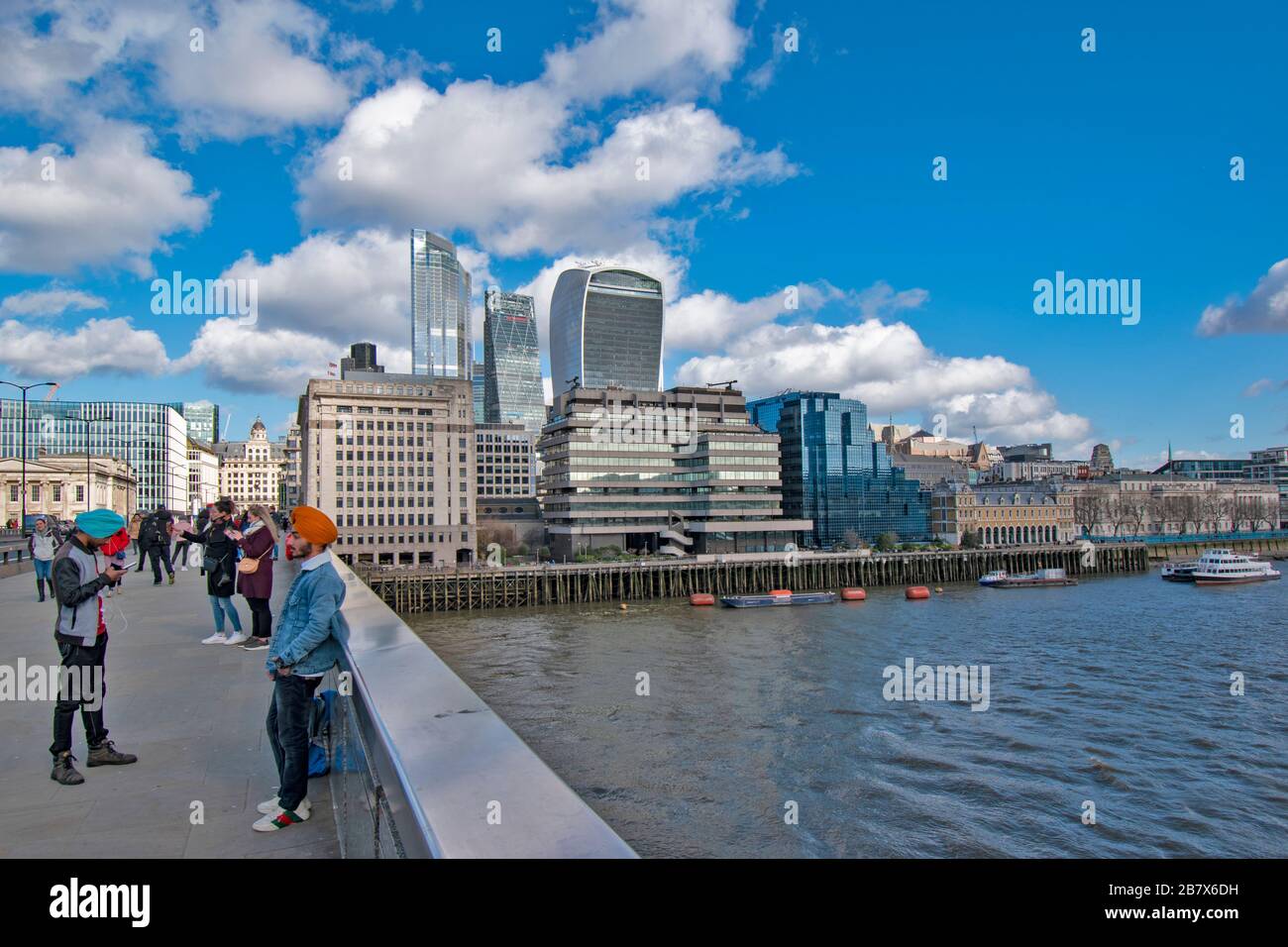 LONDON BRIDGE AND PEOPLE A VIEW ACROSS TO BUILDINGS ON LOWER THAMES STREET AND THE WALKIE TALKIE AND CHEESGRATER SKYSCRAPERS Stock Photo