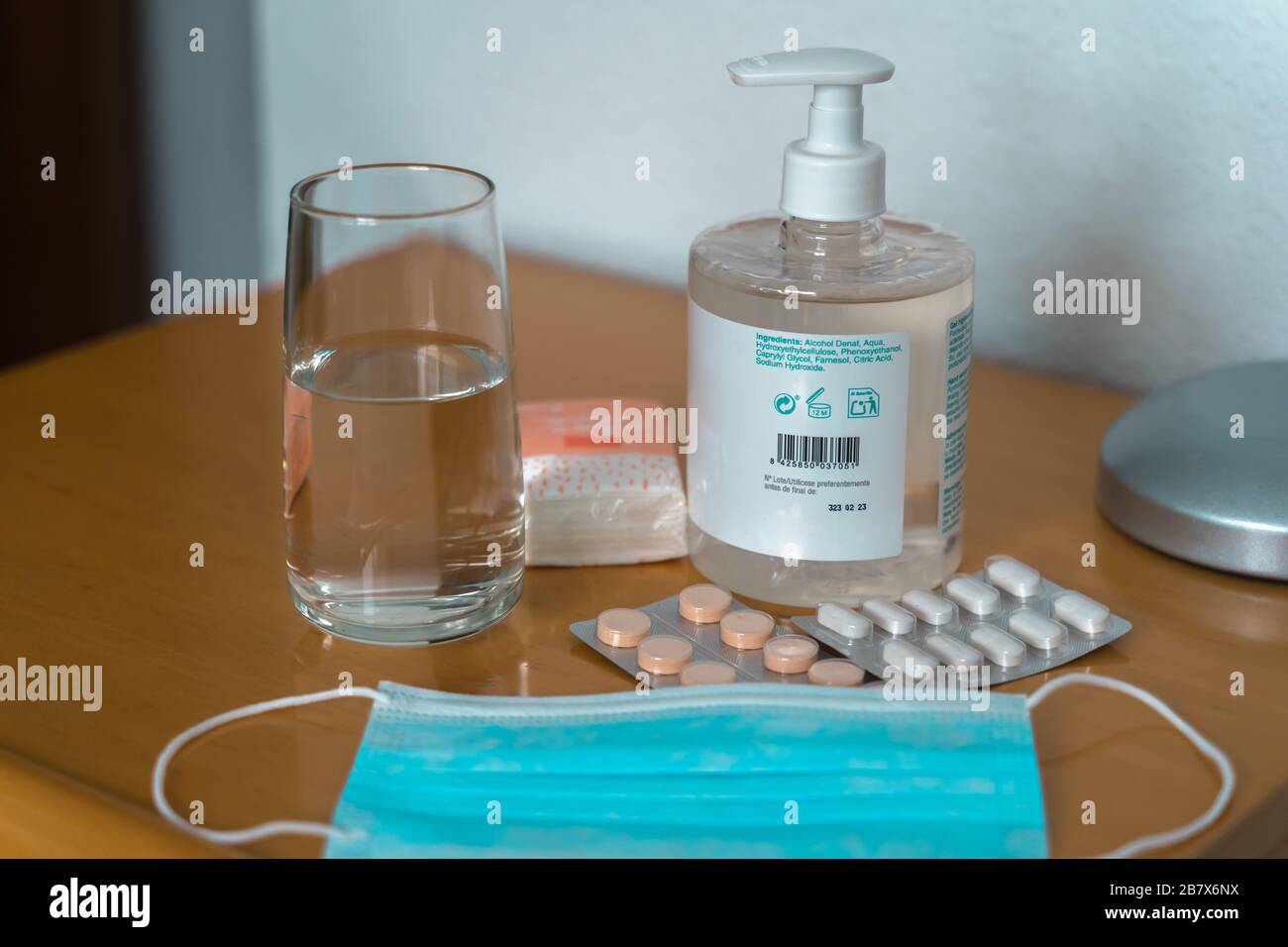Paracetamol pills, glass of water, Sanitizing Gel, tissues and medical protection mask on the bedside table. Coronovirus COVID19 outbreak quarantine k Stock Photo