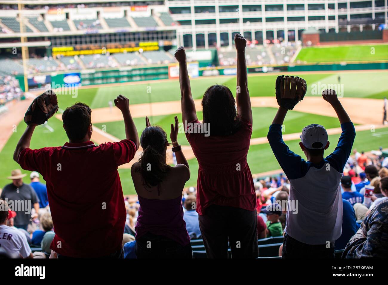 Family cheering on a baseball game at a sports stadium. Stock Photo
