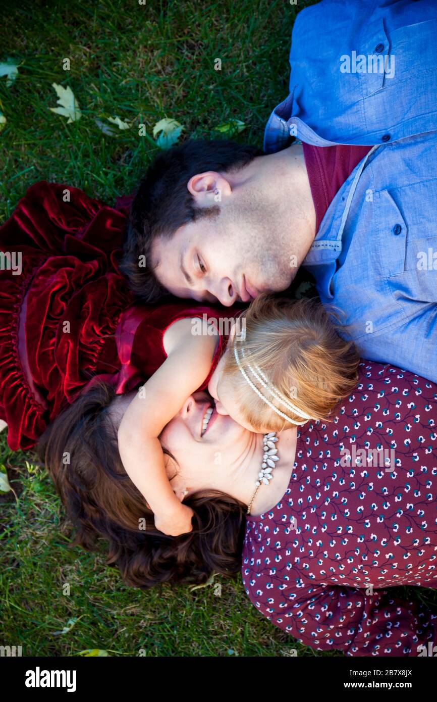 Young couple kissing daughter on grass in Detroit MI Stock Photo