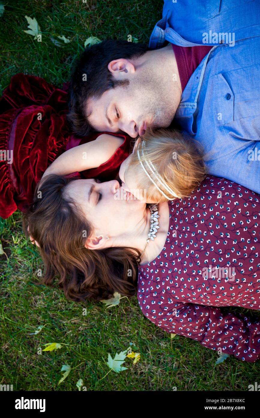 Young couple kissing daughter on grass in Detroit MI Stock Photo