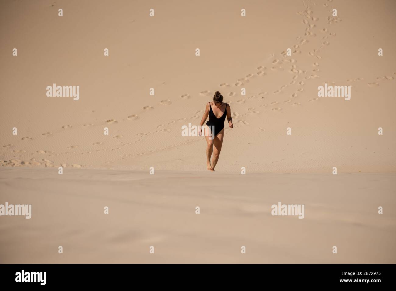 Woman in bikini climbing sand dune Stock Photo - Alamy