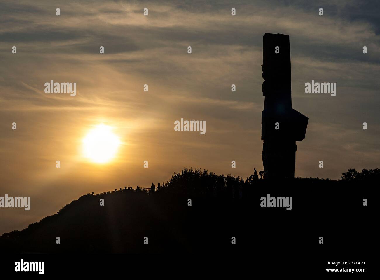 Silhouette of a 25-metre high monument of the Coast Defenders erected in 1966 with late afternoon sun in background, Westerplatte, Gdansk, Poland, Eur Stock Photo
