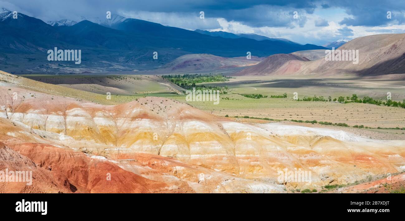 Panoramic view of the colorful mountains on a sunny day, against the backdrop of snowy peaks with dark clouds. Valley of Mars, landscapes in the mount Stock Photo