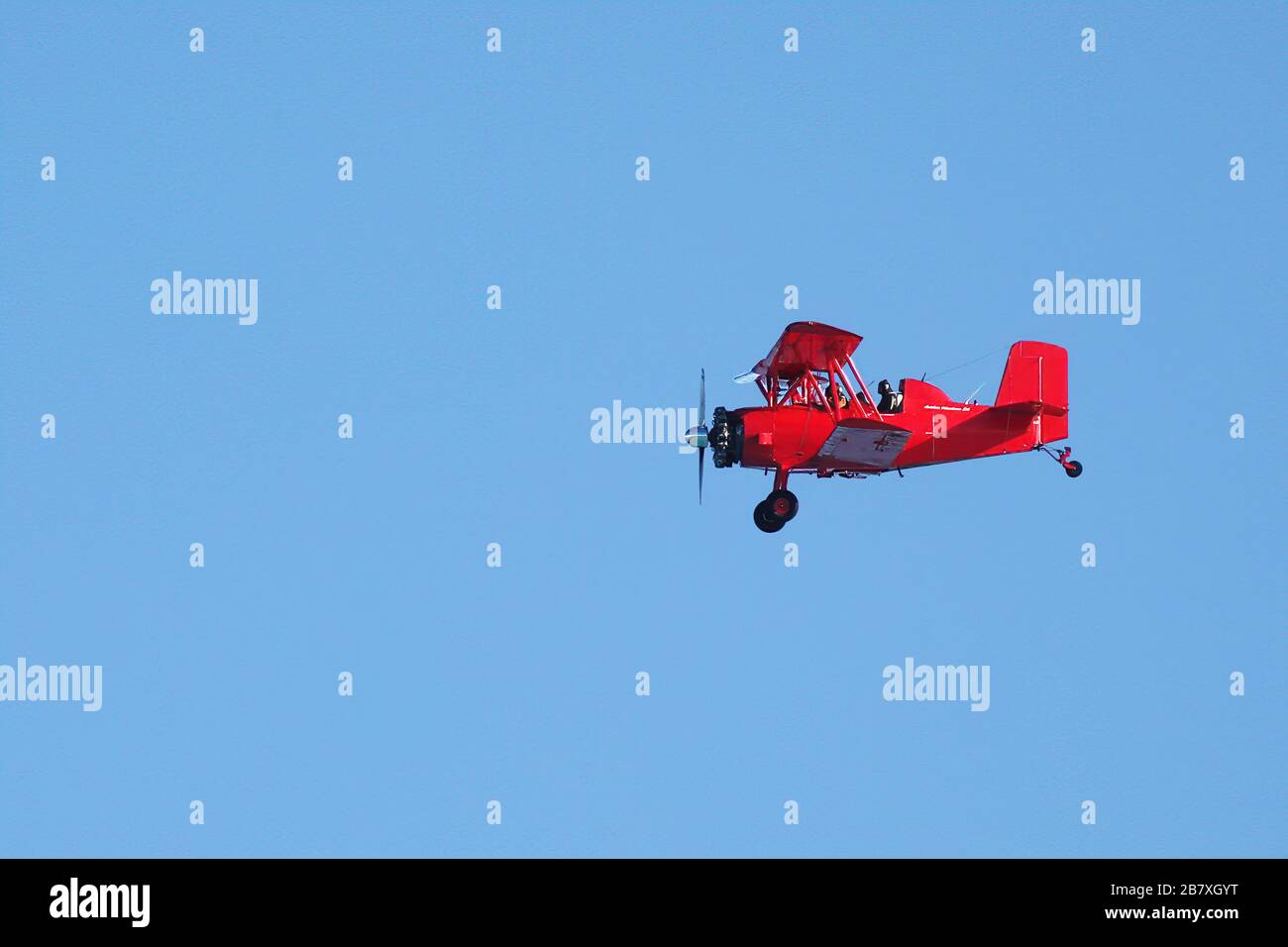 Red biplane in flight in a sunny day Stock Photo