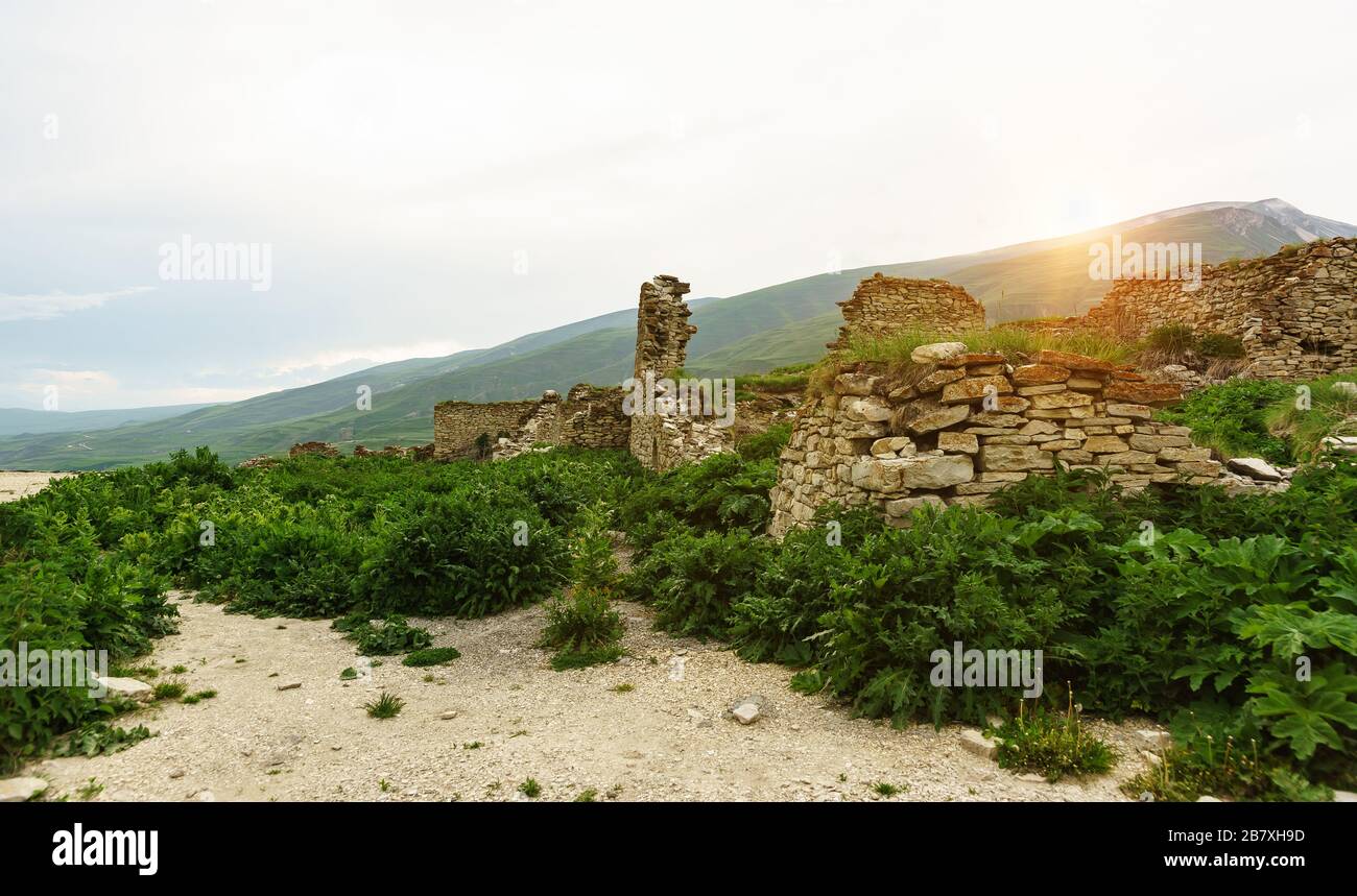 Overgrown stone ruins in the ancient city of Hoi an in the background the beautiful mountains of Big Kavkaza sunset. Stonework without any binding mor Stock Photo