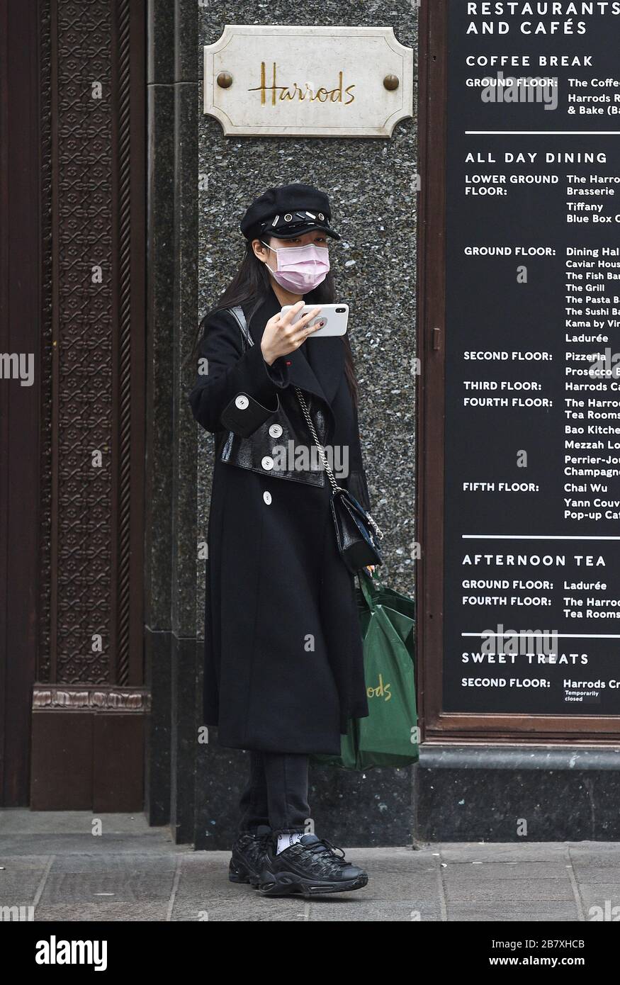 A woman wearing a mask outside Harrods in Knightsbridge, London after the department store cut back opening times. Stock Photo
