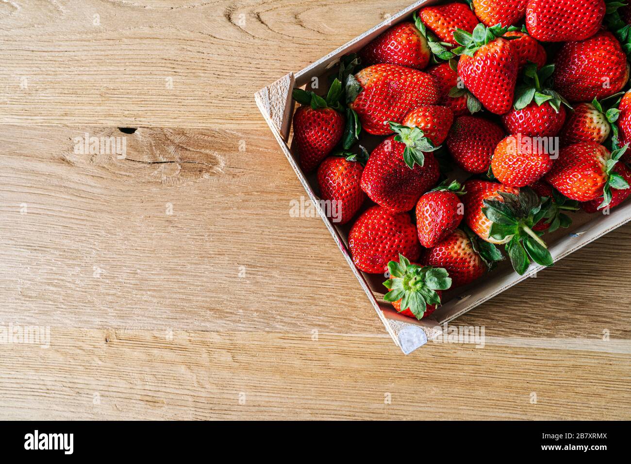 A box of fruit filled with strawberries viewed from above on a wooden table Stock Photo