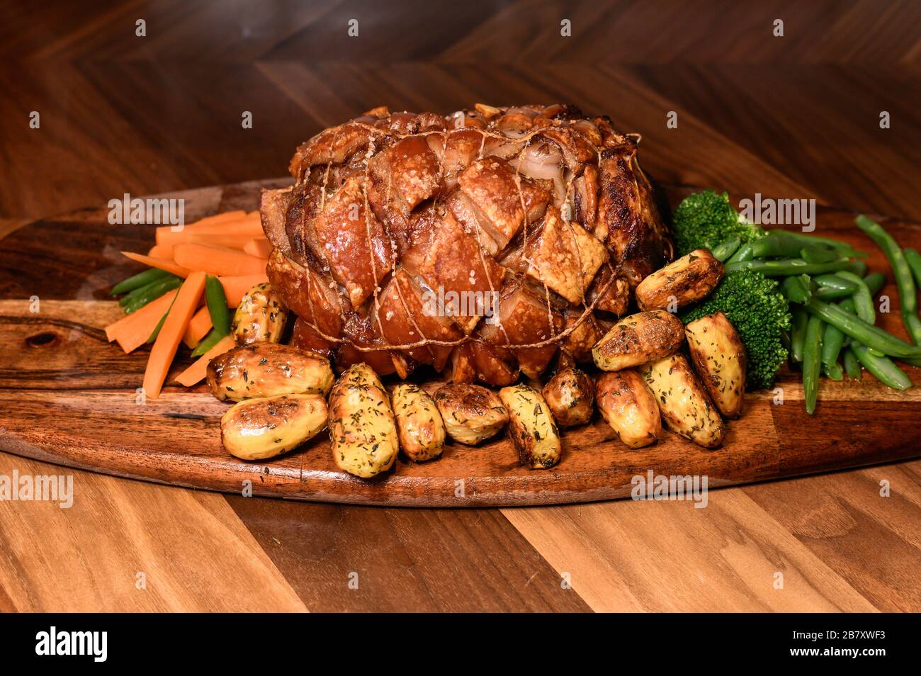 Hogs Back Toppings hog roast pork decorated with patatos and veg on wooden board and ...
