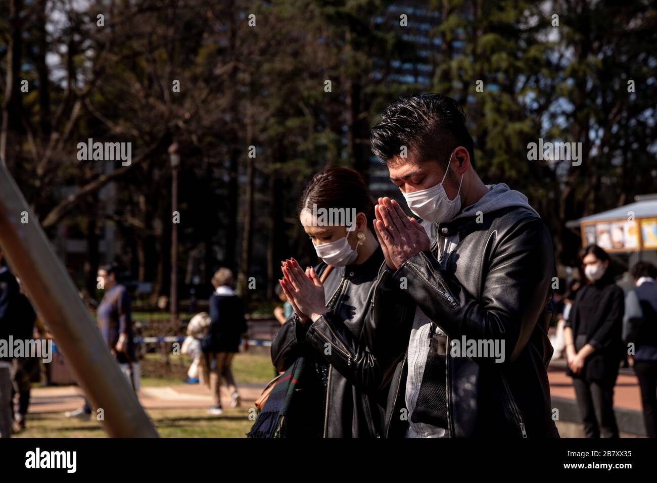 A couple wearing masks as a preventive measure, praying at the 9th anniversary of the 311 mega-earthquake and tsunami during the corona virus pandemic.Concerns are growing about the increasing cases of Coronavirus (COVID-19) in Japan. Many countries have closed borders to Japan and the growing epidemic has caught public attention on the true number of coronavirus cases in Japan that could be much higher. Stock Photo