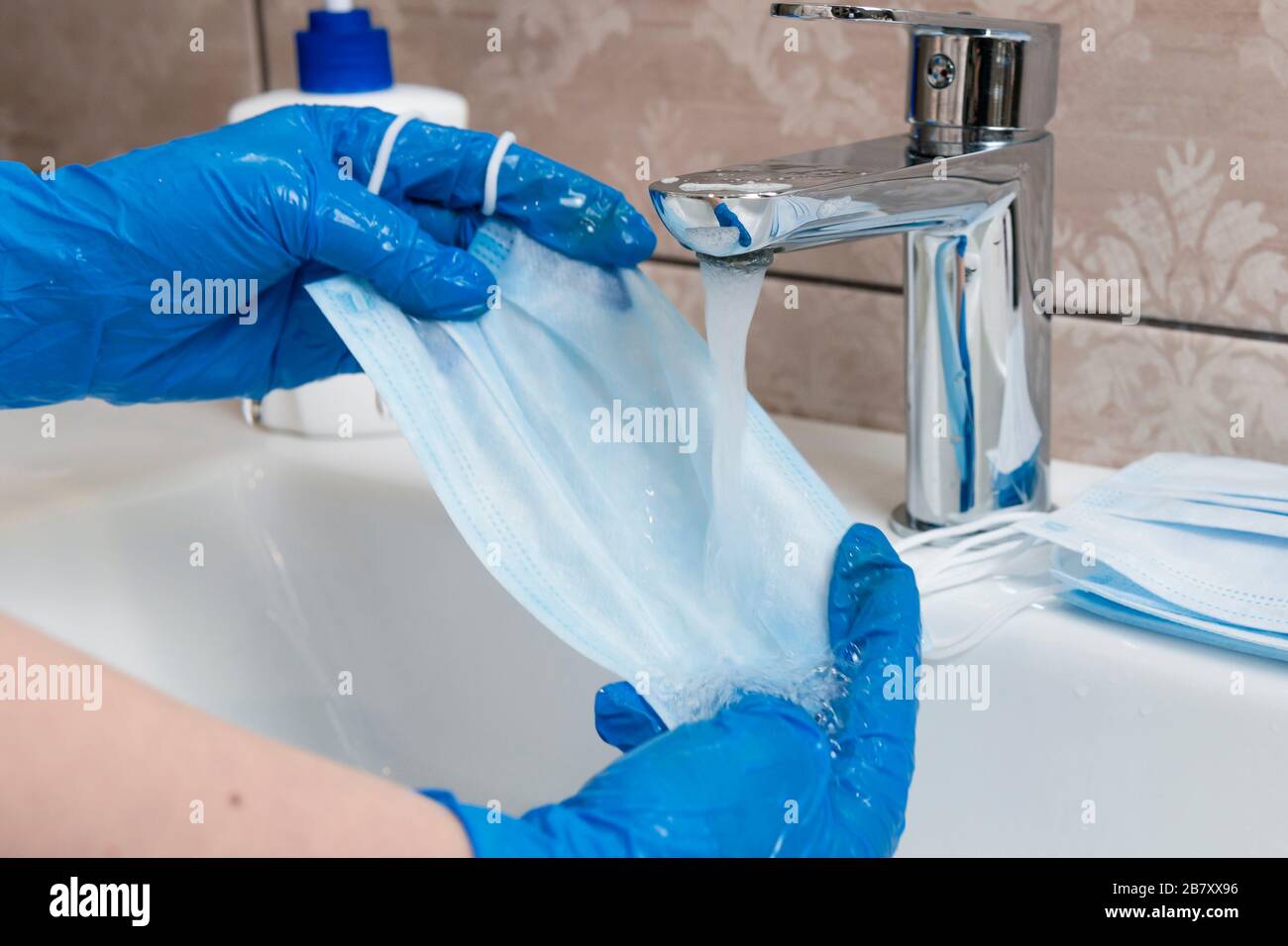 Closeup of female hands washing disposable medical face mask with soap