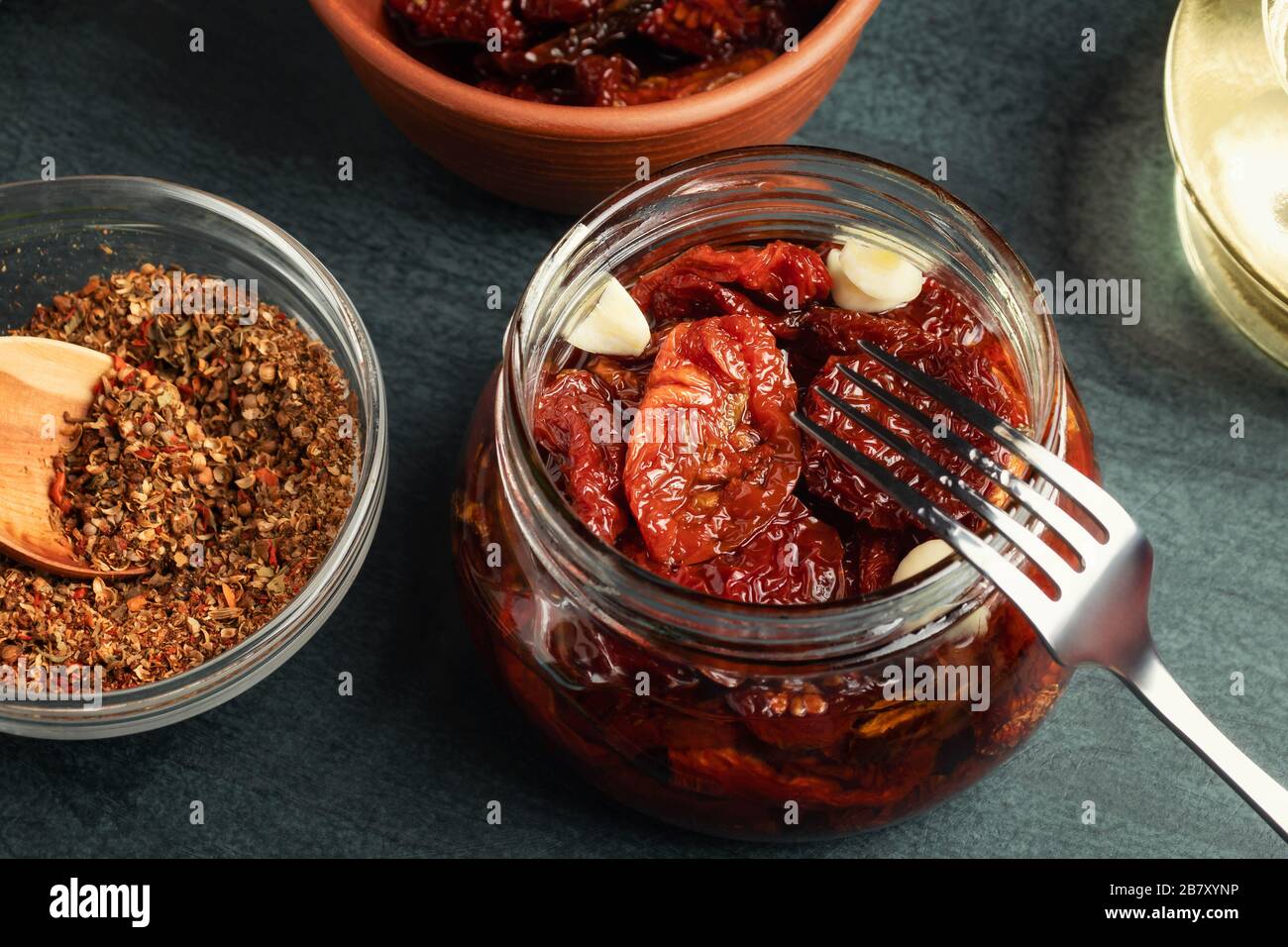 Cooking sundried tomatoes in a glass jar with olive oil, garlic and
