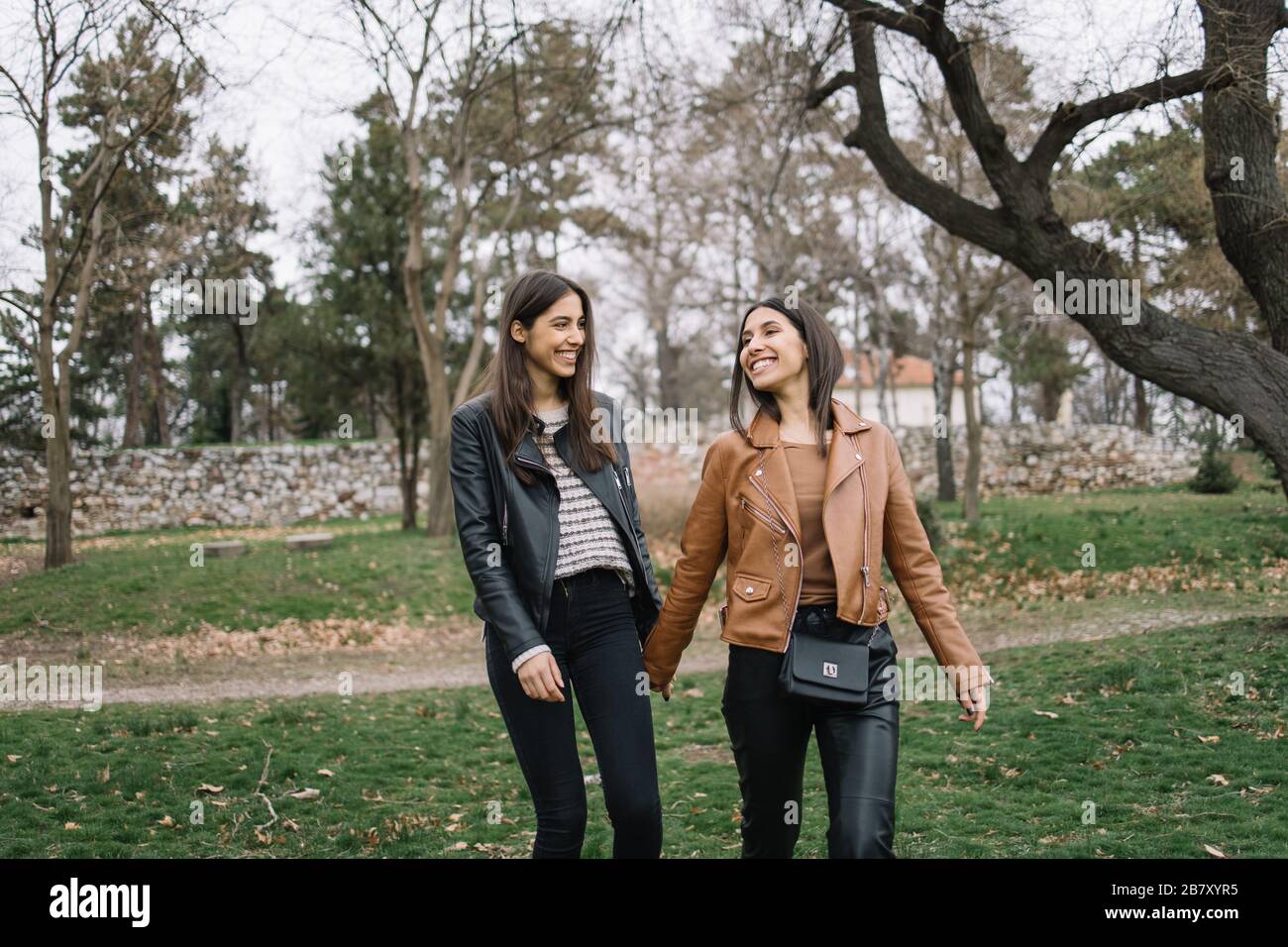 Smiling women holding hands in the woods Stock Photo - Alamy