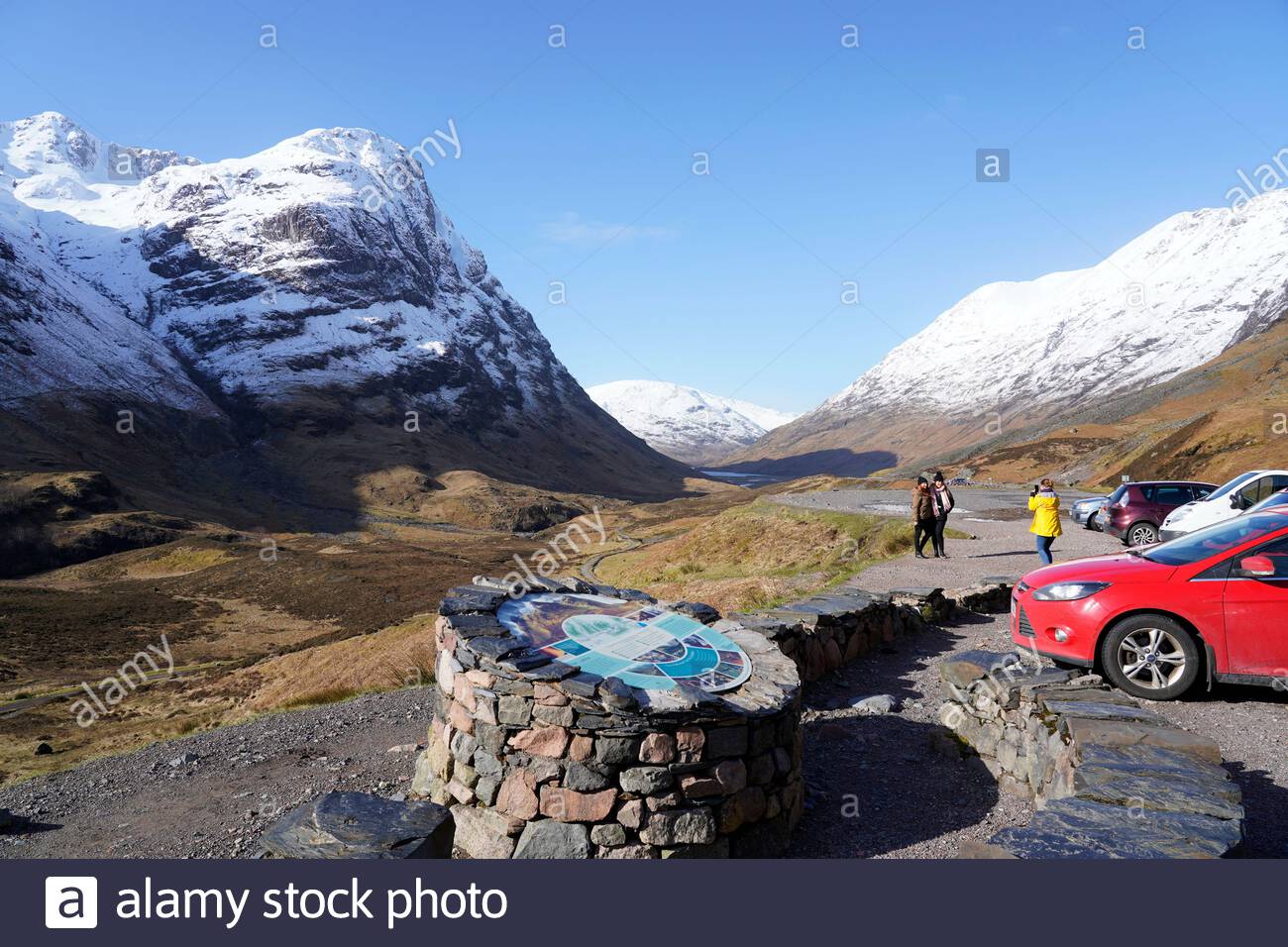 Sun and snow in the Scottish Highlands, Glencoe seen here being affected. Visitors and carpark at the Three Sisters Ridge. Scotland. Stock Photo