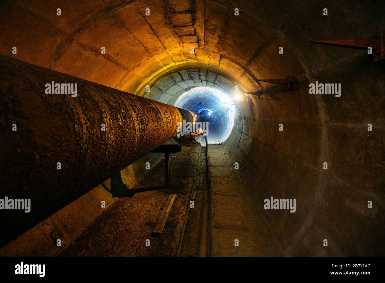 Round concrete underground tunnel of heating duct system with rusty pipes Stock Photo