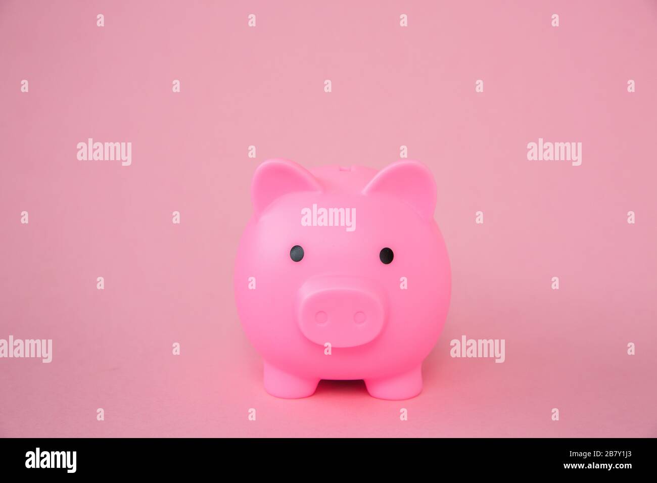 A pink kids Piggy Bank on a pink background with copy space in a savings concept background image Stock Photo
