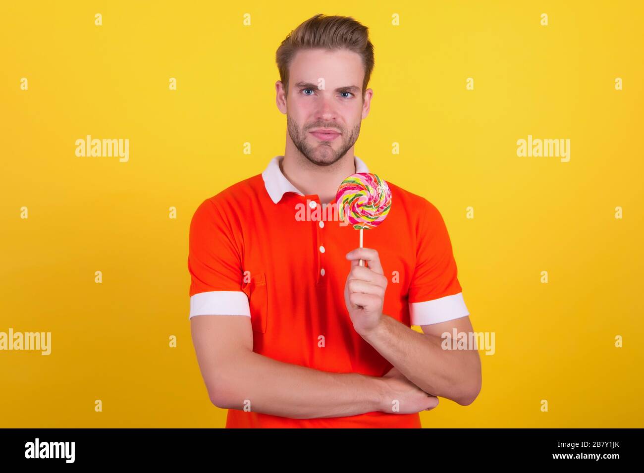 Taste the rainbow. Man candy yellow background. Handsome guy hold candy on stick. Candy shop. Lollipop or sucker. Sugary treat. Candy factory and confectionary. Stock Photo
