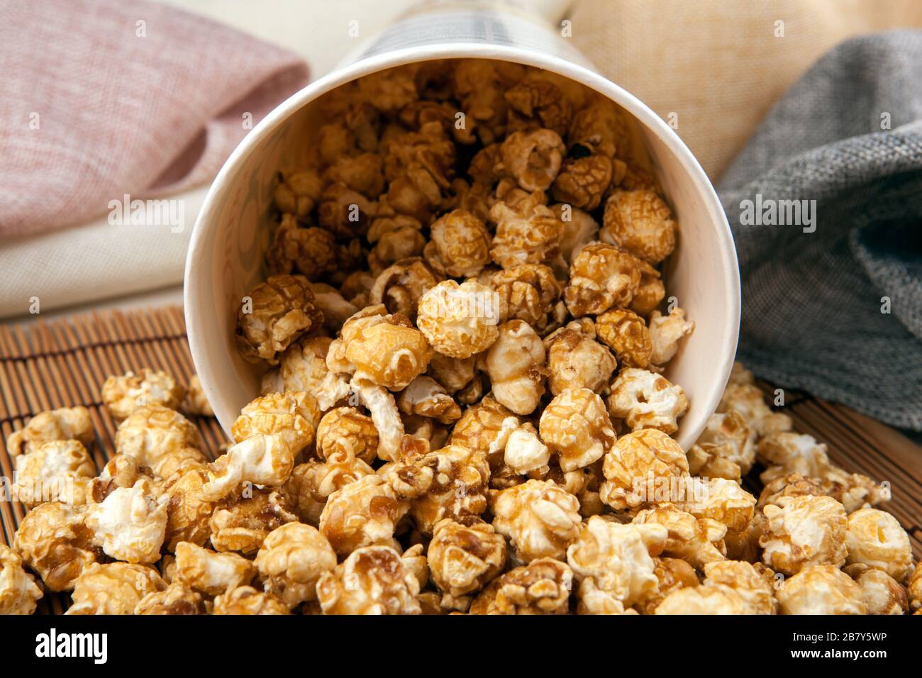 big cardboard cup with sprinkled sugar popcorn on a bamboo napkin top view Stock Photo