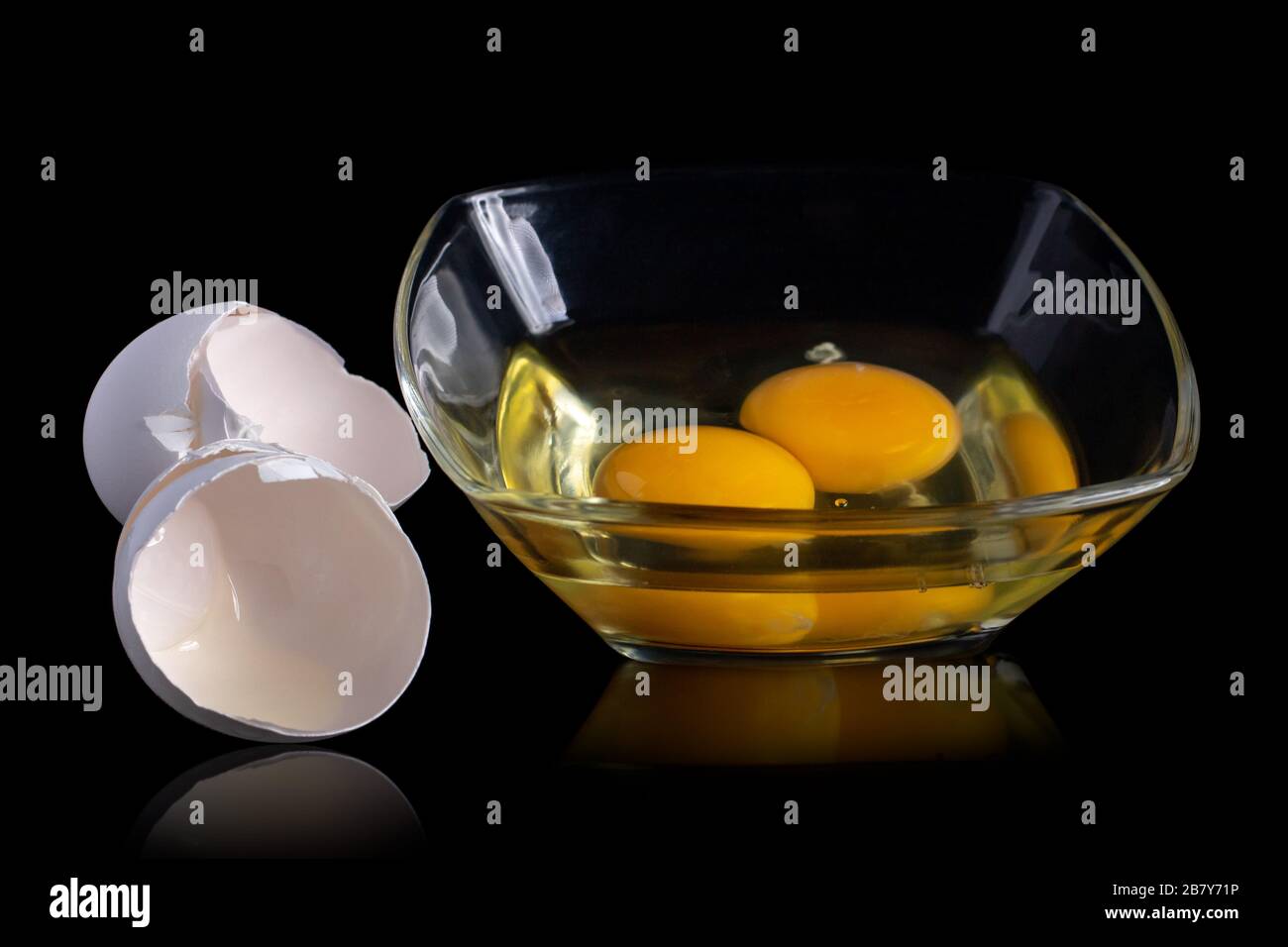 broken eggs yolk in a glass bowl isolated on a black background, egg ...