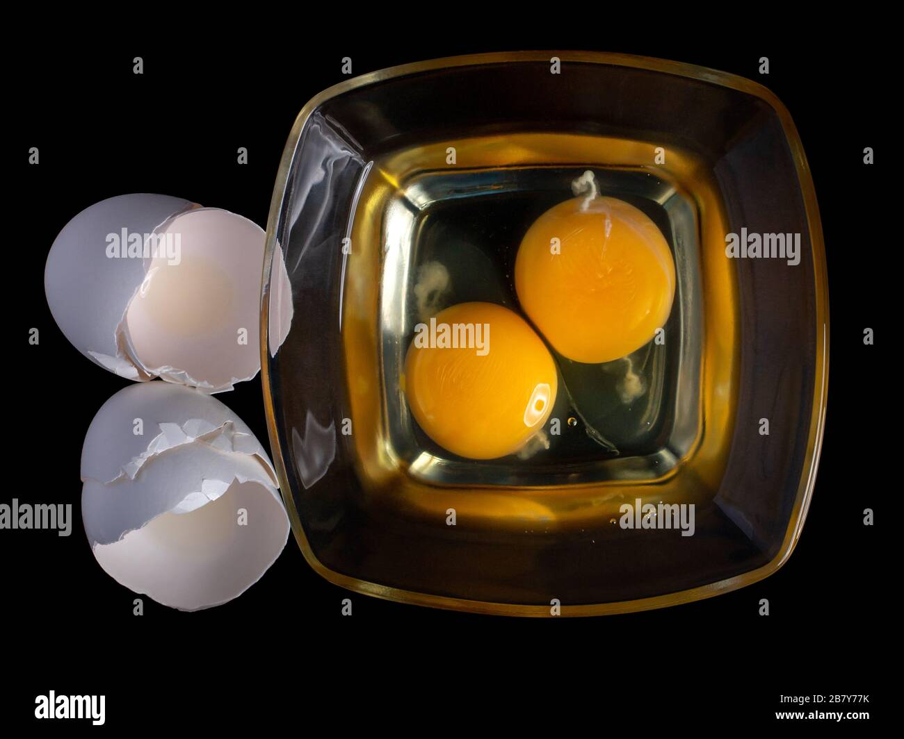 broken eggs yolk in a glass bowl isolated on a black background, egg ...