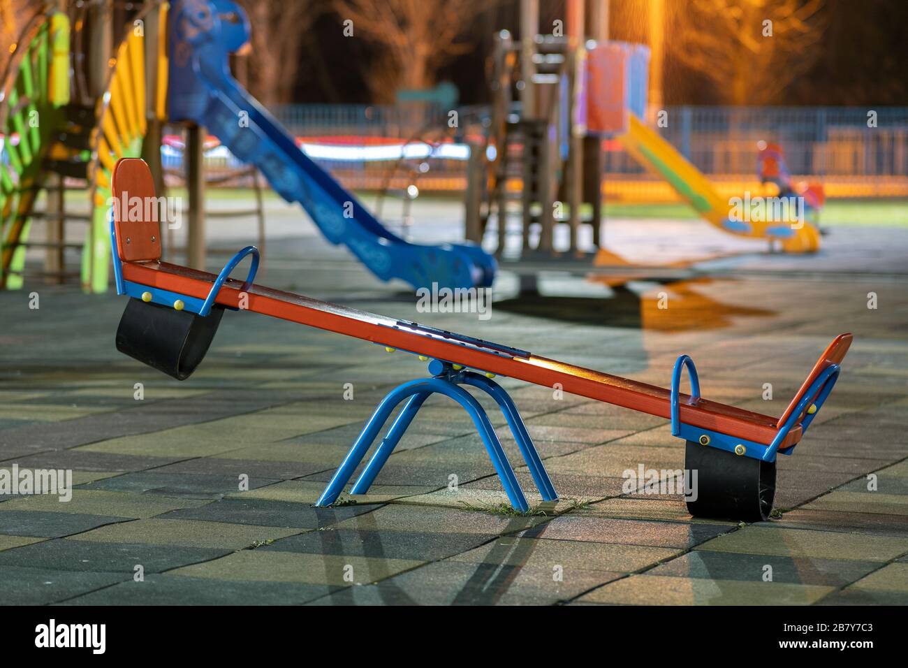 Seesaw swing in preschool yard with soft rubber flooring at night. Stock Photo