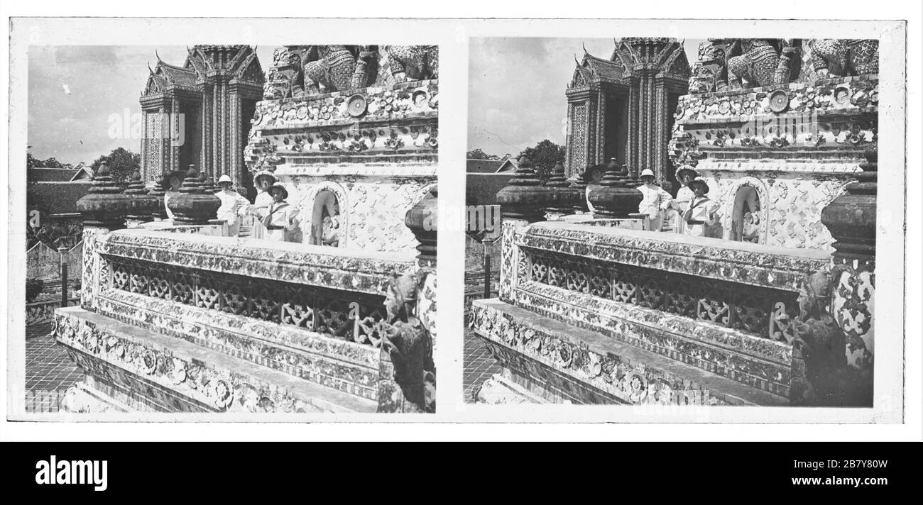 Wat Arun temple (Temple of dawn) in Bangkok. European tourists standing on a first level balcony of the central Prang (Phra Prang); above the group Yakshas who hold as Caryatids level two. In the background one of the small prangs. Stereoscopic photograph from around 1910. Photograph on dry glass plate from the Herry W. Schaefer collection. Stock Photo