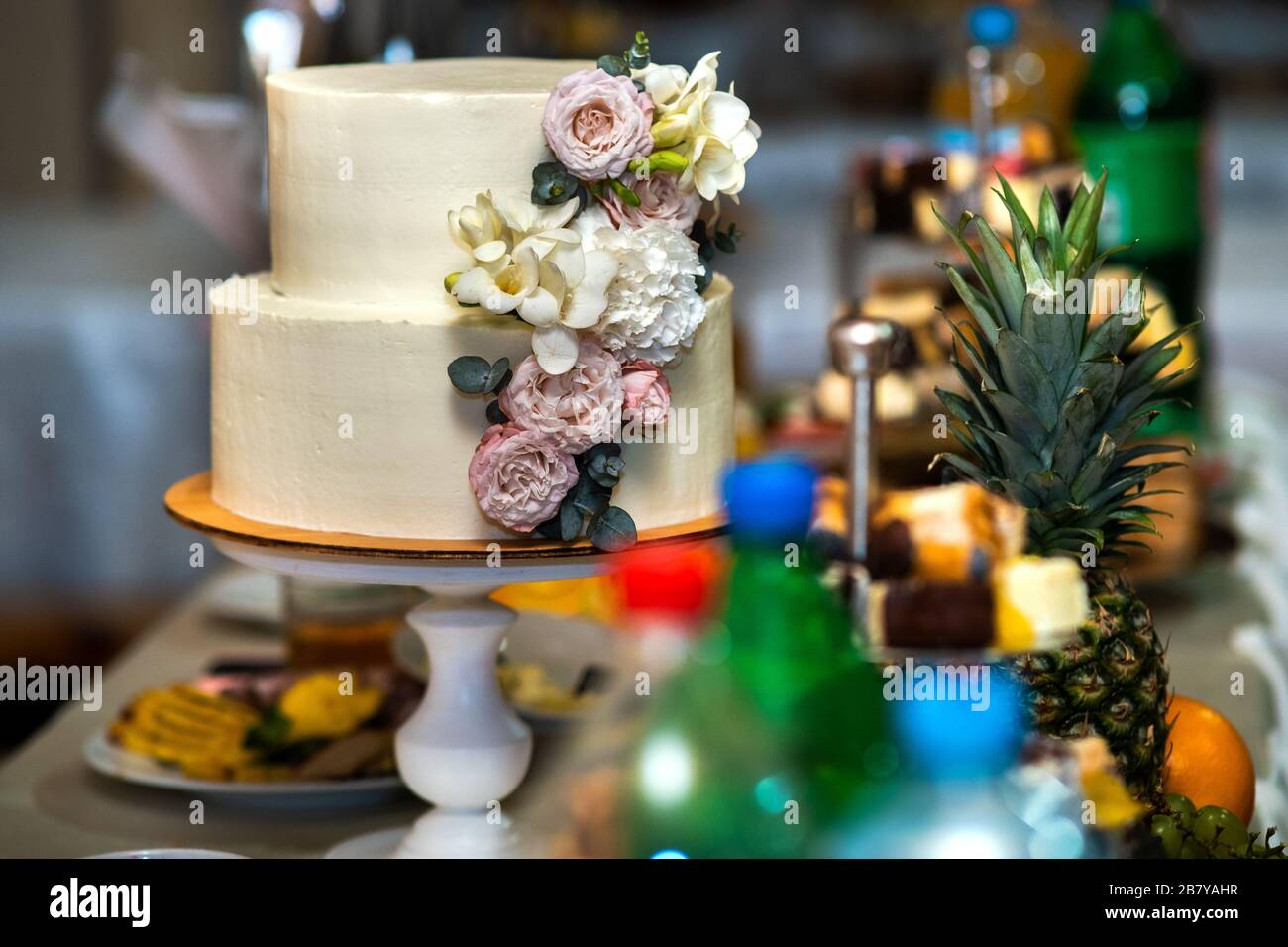 Tall sweet wedding cake decorated with live pink and white flowers on a ...