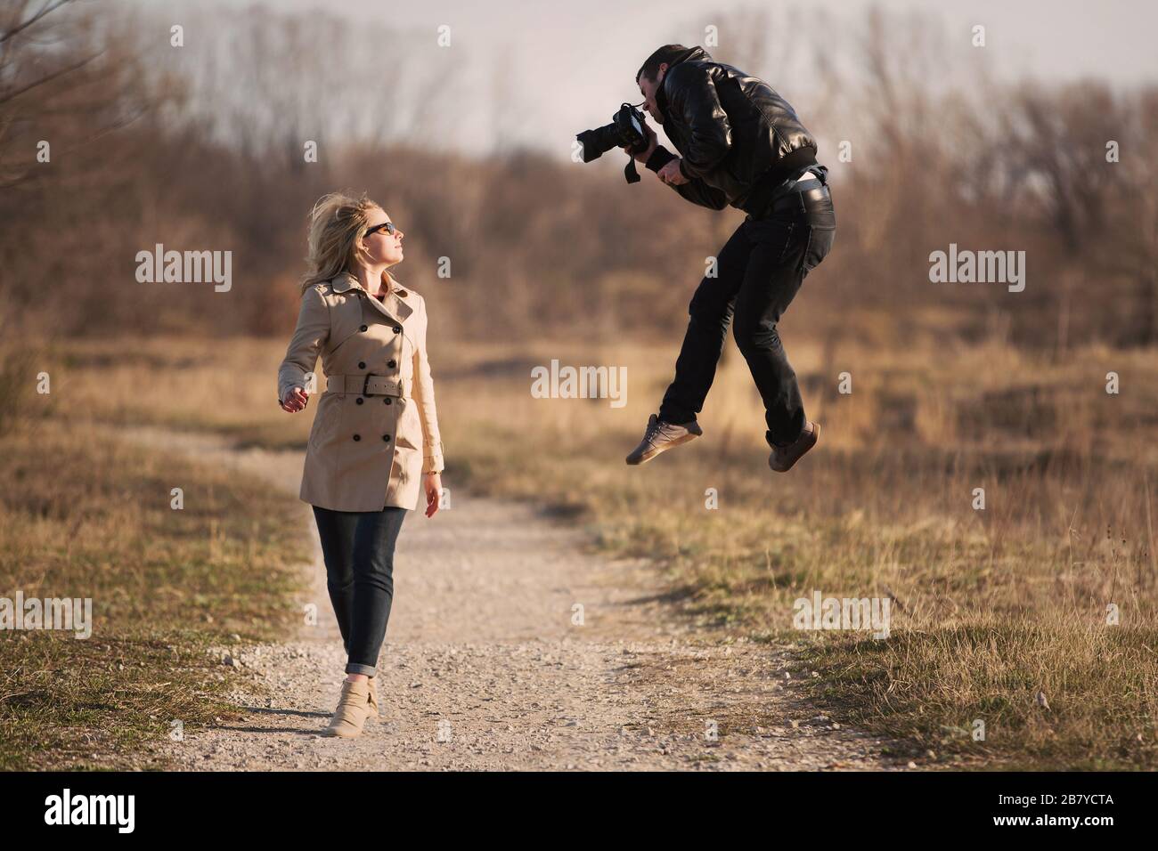 athletic photographer jumping to capture photo of young woman Stock Photo