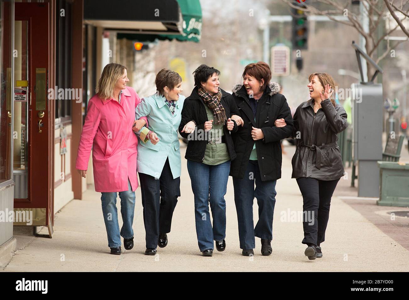 Middle aged women walking and laughing wtih linked arms Stock Photo