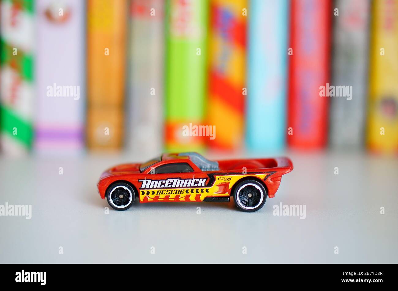 POZNAN, POLAND - Mar 12, 2020: Hot Wheels Mattel Bedlam toy car on a wooden shelf with colorful books in soft focus background. Stock Photo
