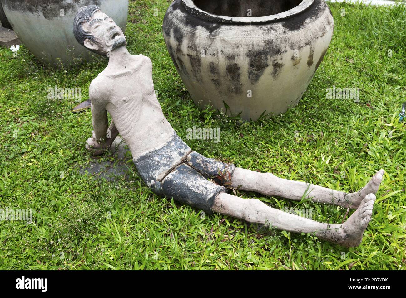 Figure of Tortured Prisoner Lying on Grass in Tuol Sleng War Crimes Genocide Museum, Phnom Penh Cambodia Stock Photo