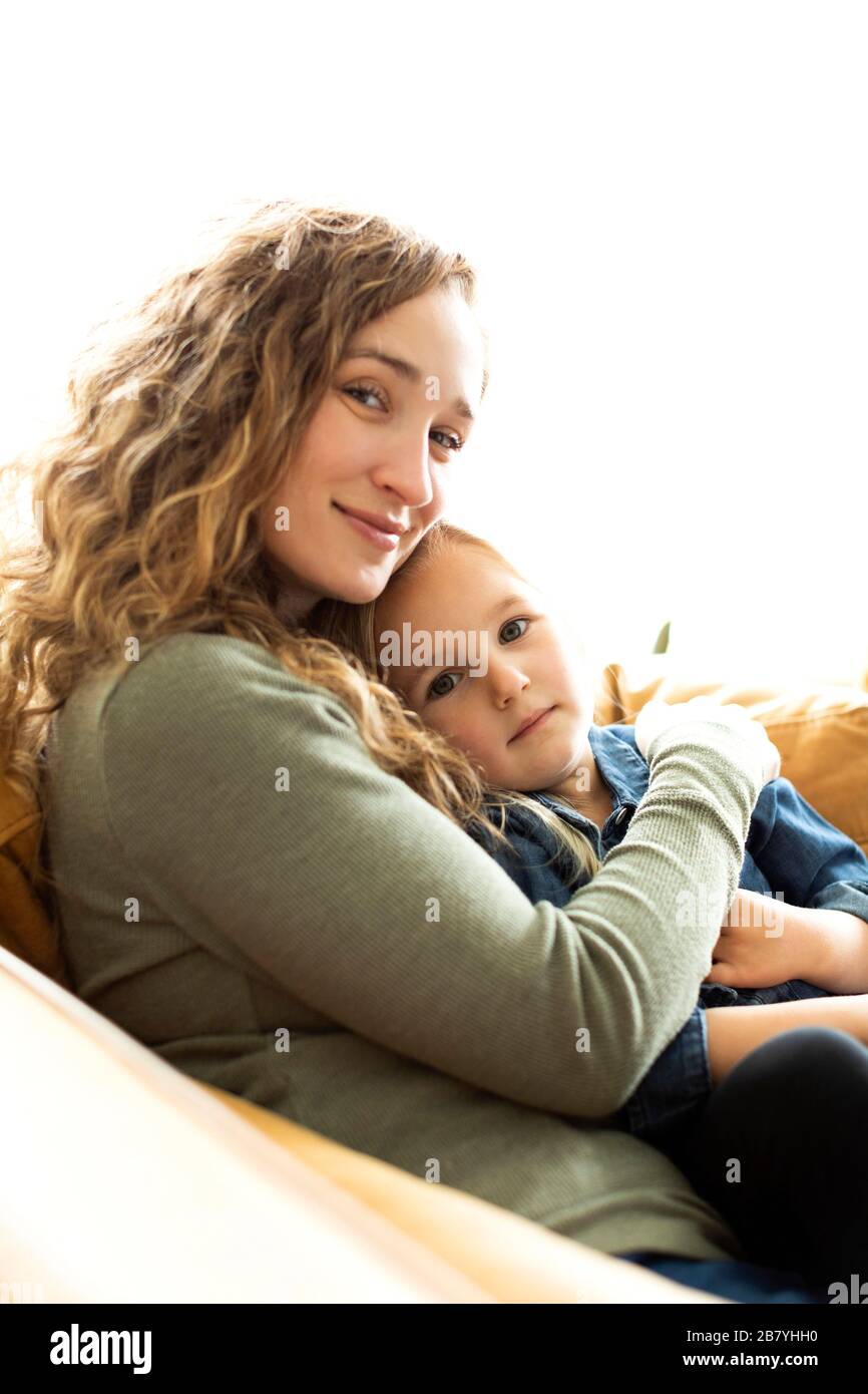 Mother and daughter sitting on sofa Stock Photo