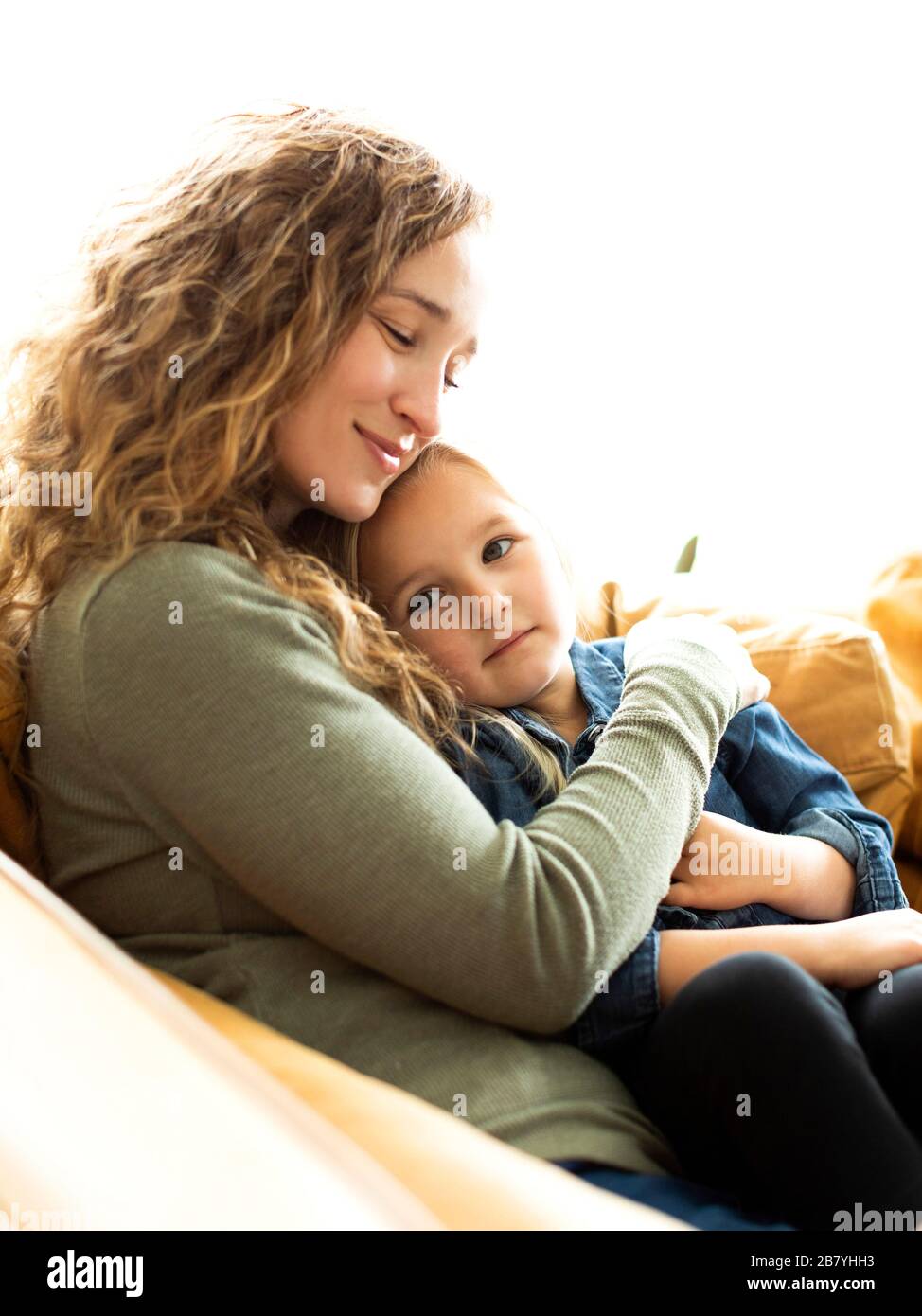 Mother and daughter sitting on sofa Stock Photo