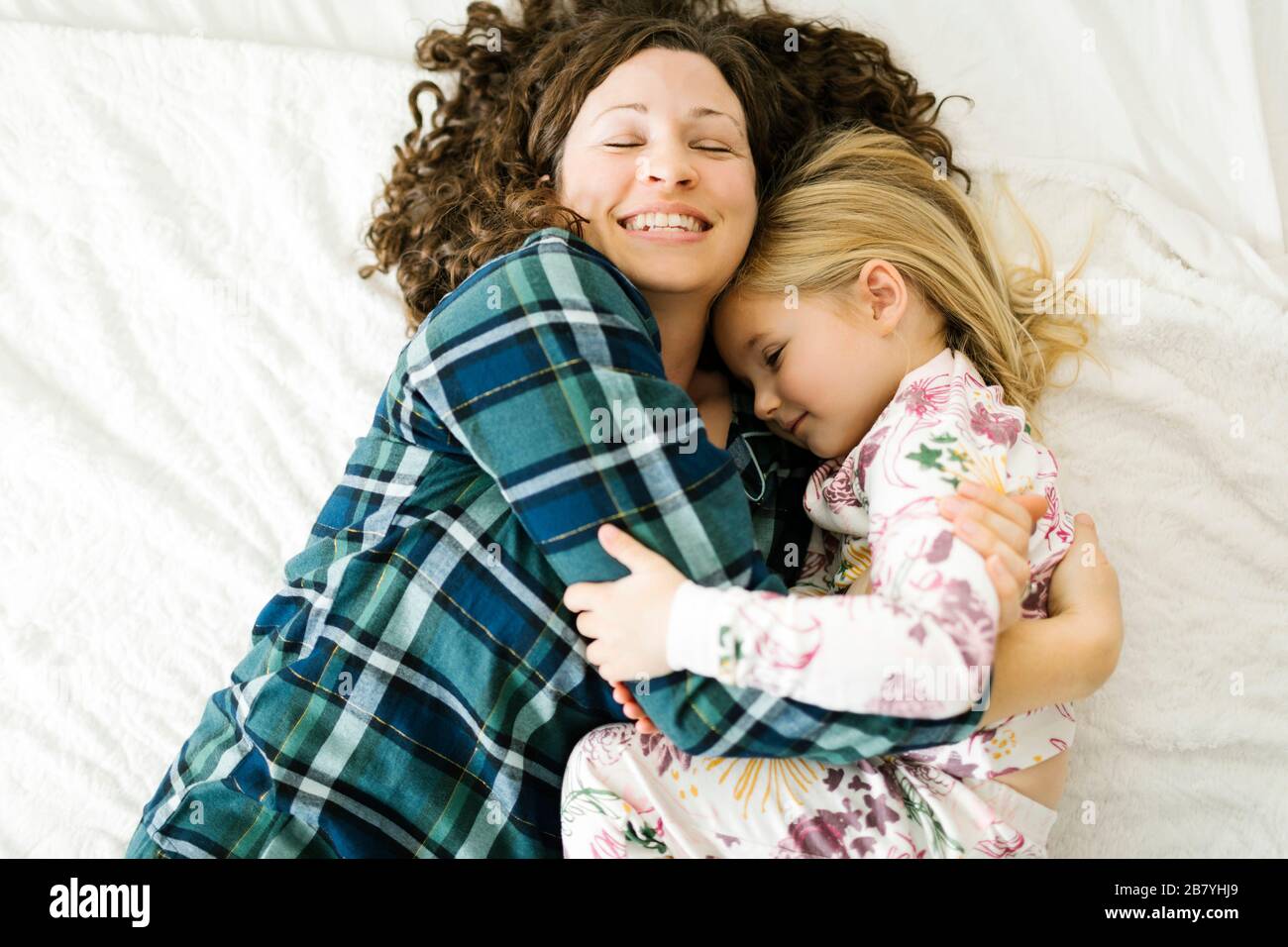 High angle view of mother and daughter in pajamas lying on bed Stock Photo