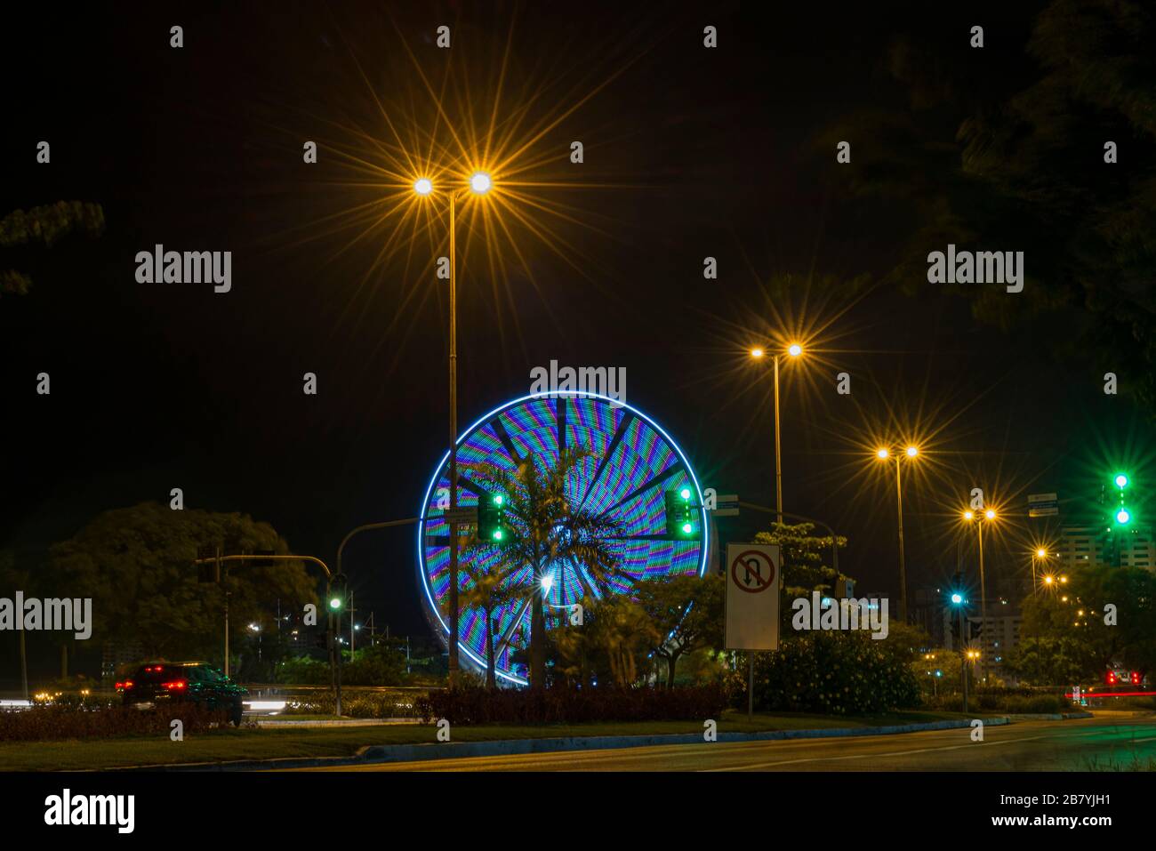 Long exposure of colorful ferris wheel and light trails on the expressway road at night. Time exposure of traffic lights on avenue in Florianopolis. C Stock Photo