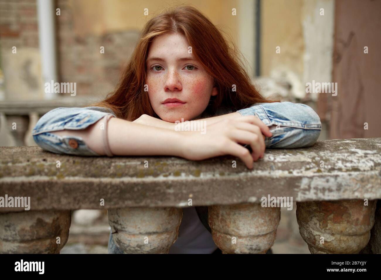 Teenage girl leaning on stone banister Stock Photo