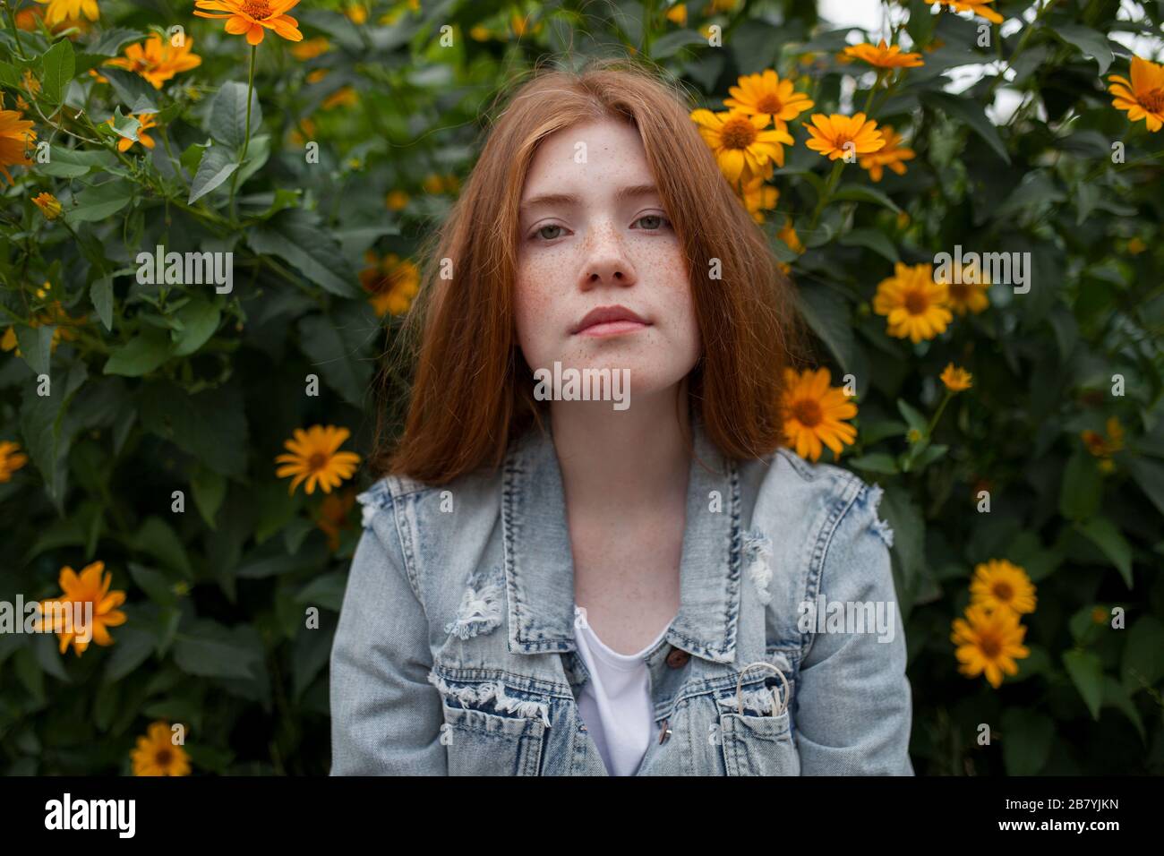 Teenage girl by bush with orange flowers Stock Photo