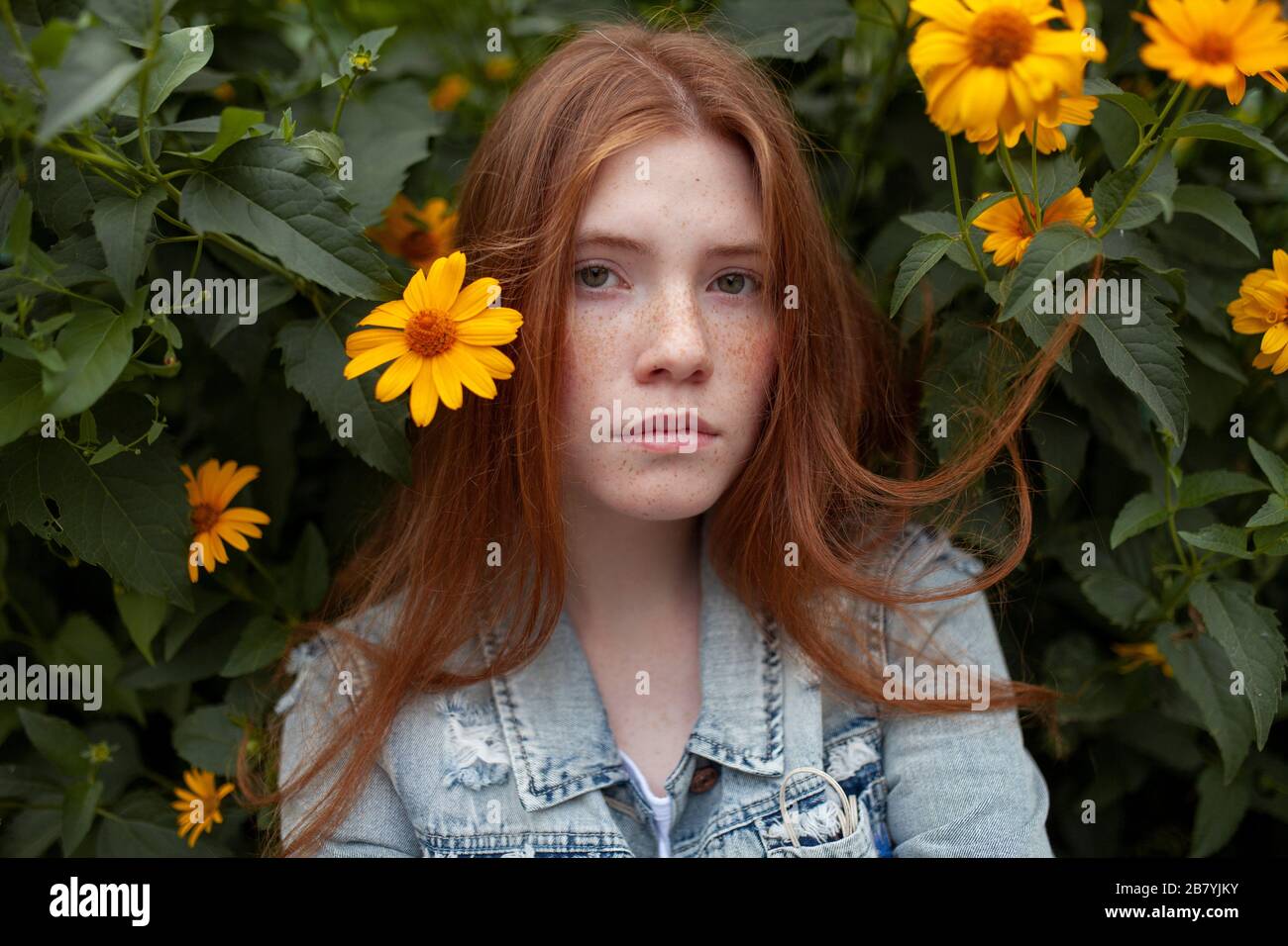 Teenage girl by bush with orange flowers Stock Photo
