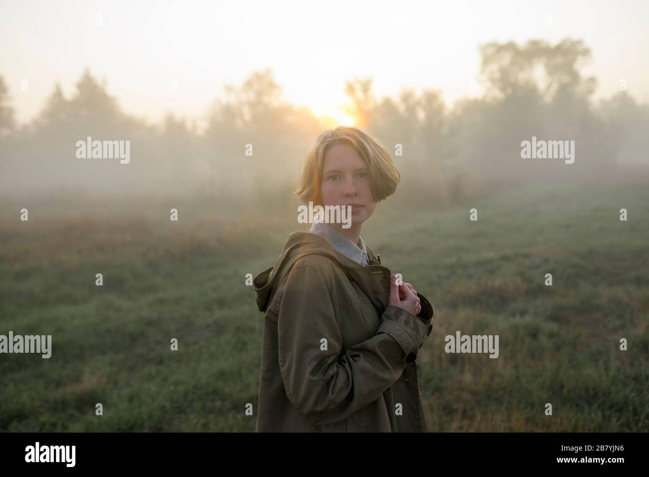 Young woman in field at sunset Stock Photo