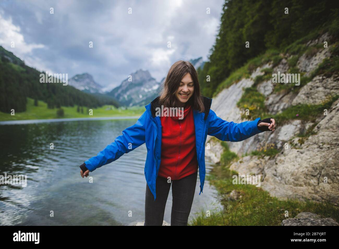 Smiling young woman in blue jacket by lake Stock Photo