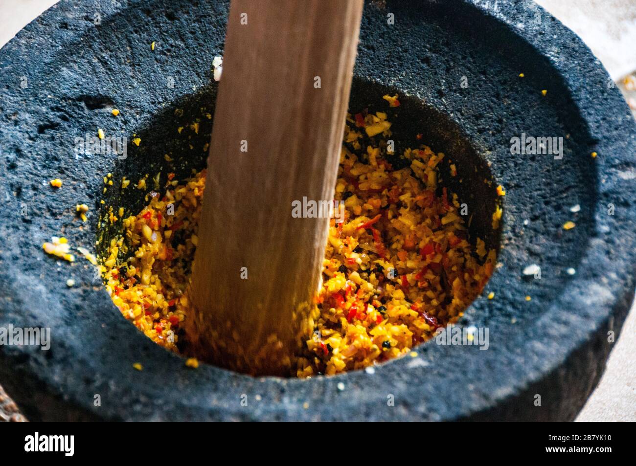 Balinese basic yellow sauce being made in a traditional lesung, mortar and pestle, Stock Photo