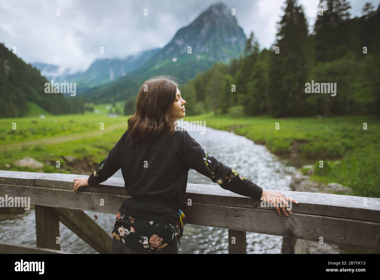 Young woman leaning on railing by river Stock Photo