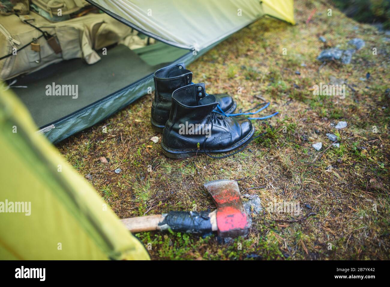 Boots and hatchet by tent Stock Photo