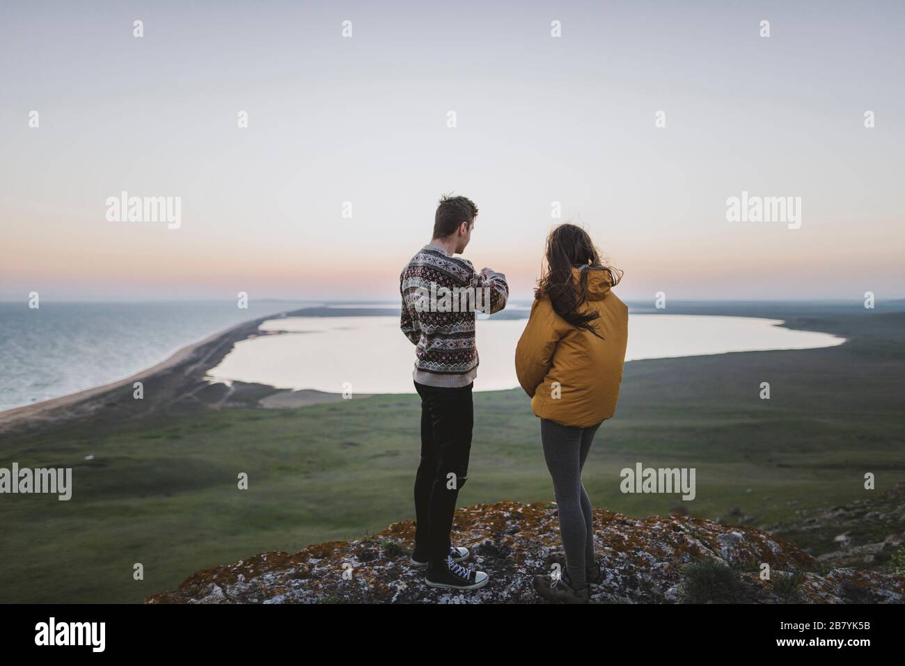 Young couple standing on hill at sunset Stock Photo