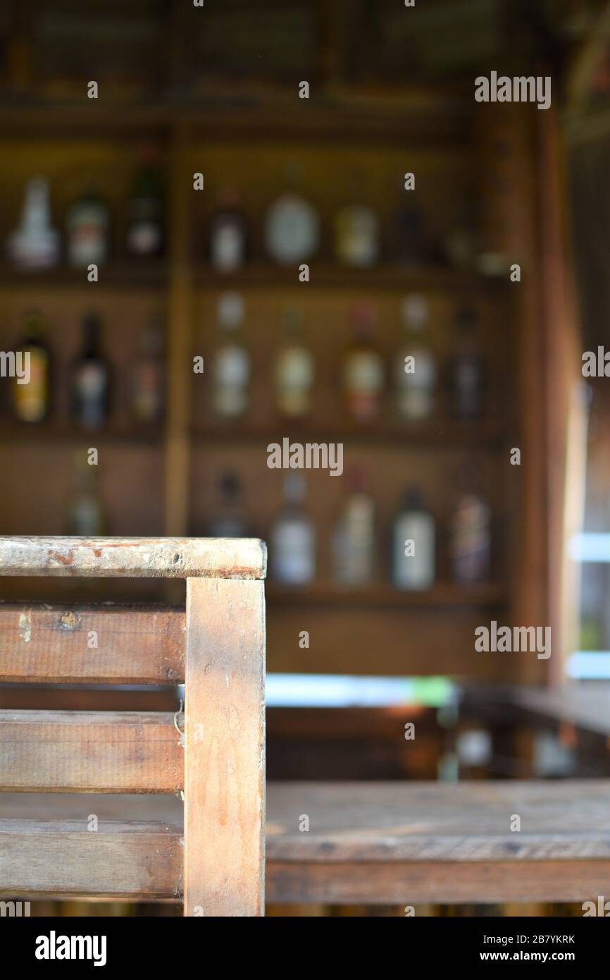 An empty wooden stool in an outdoor bar with rows of liquor bottles in the background Stock Photo