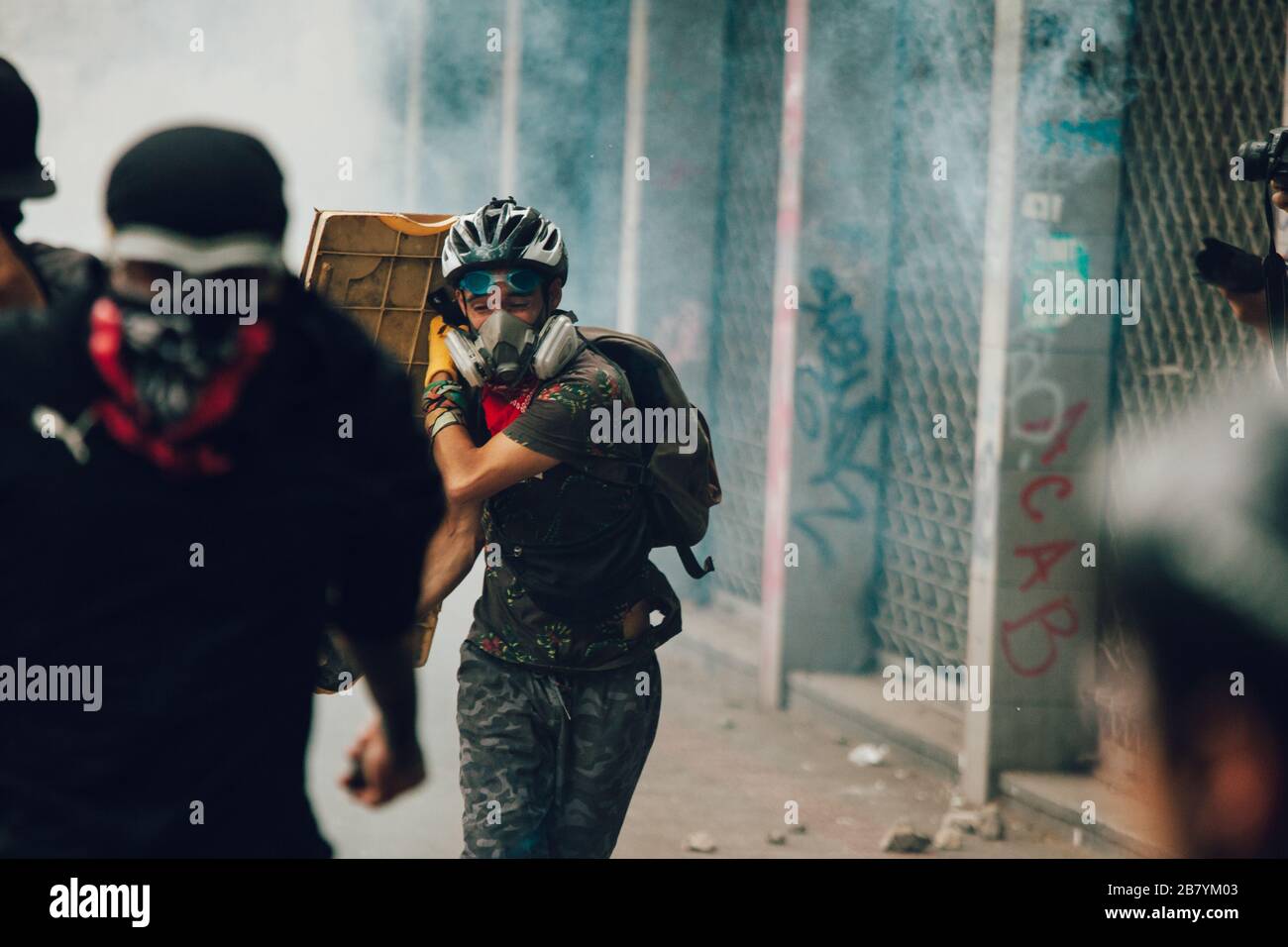 SANTIAGO, CHILE-NOVEMBER 8, 2019 - Protester runs away from tear bombs during the protests against the government of Sebastian Pinera, for the social Stock Photo