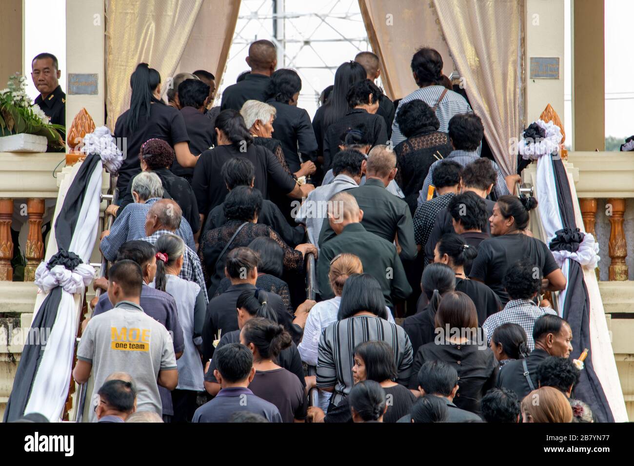 NAKHON NAYOK, THAILAND, SEP 29 2019, A funeral guests walks up the stairs up to the deceased's coffin. Queue of people advancing up to the crematorium Stock Photo
