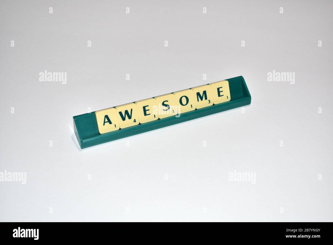 Scrabble tiles spell out Awesome. Motivational quote Scrabble Blocks Letters Grey Background Life quote Induce Alphabet. Stock Photo